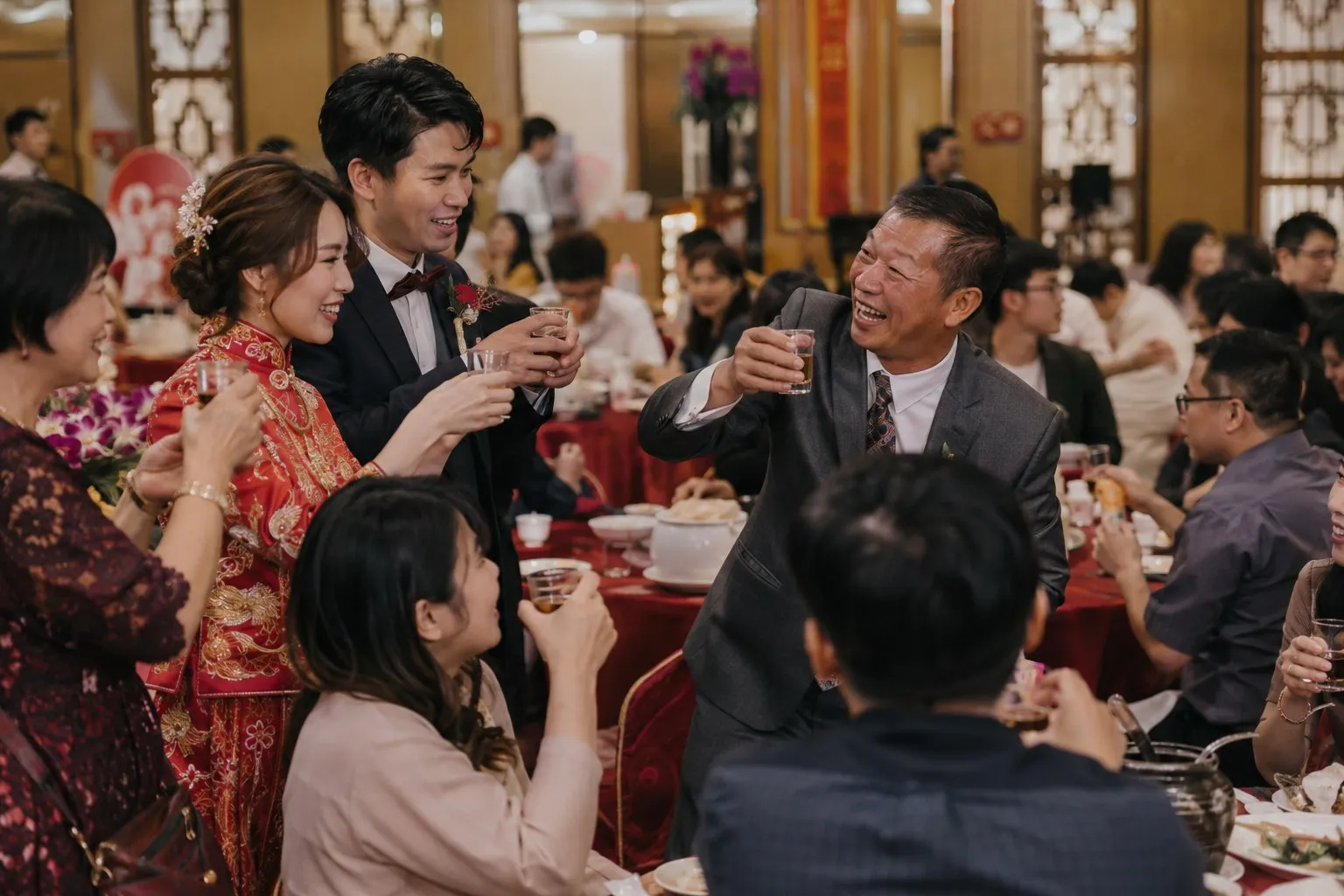 宴客的圓桌之間，新人舉杯，對面的長輩舉著杯子大笑
