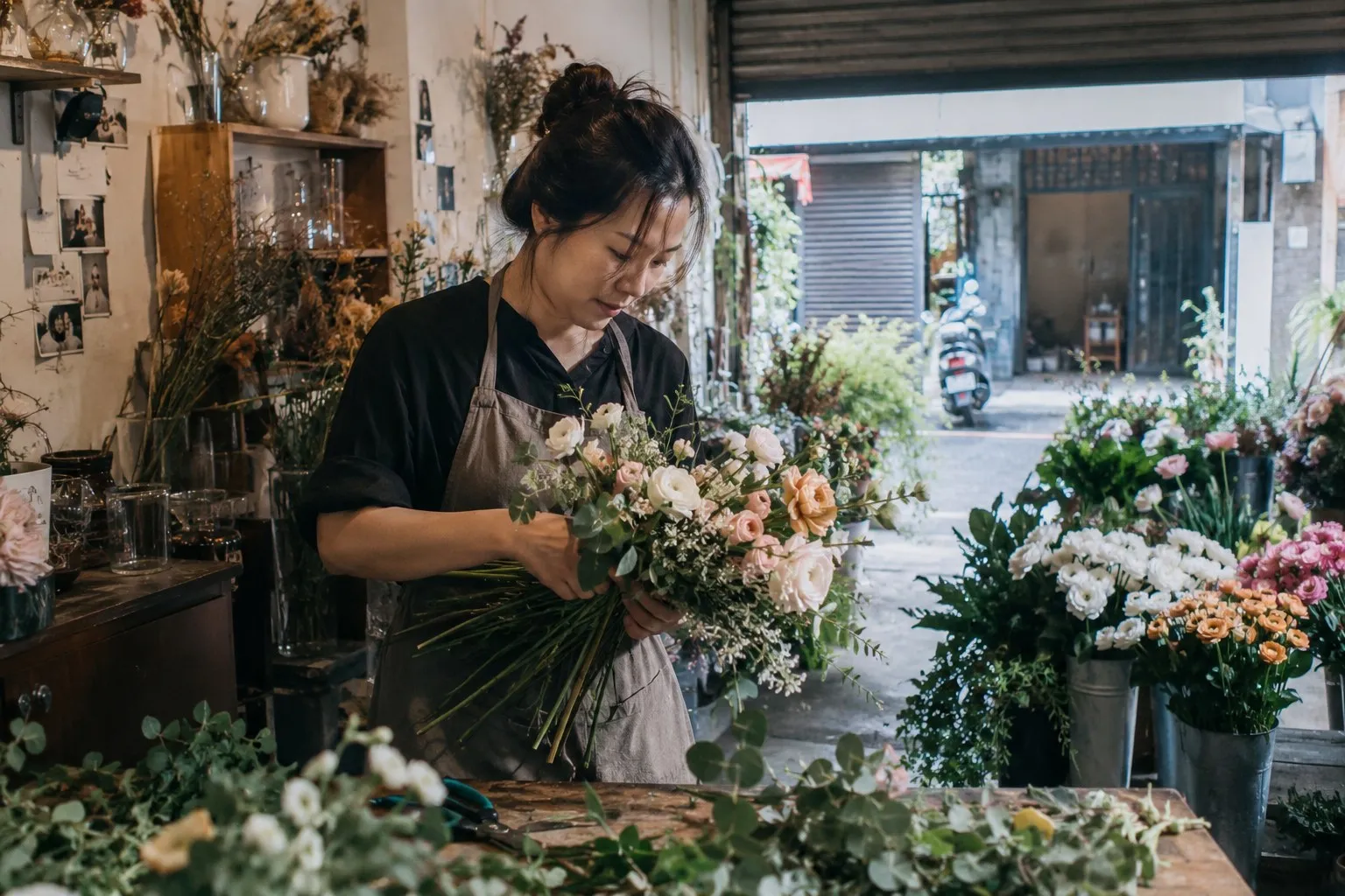 花店的工作檯前，老闆抱著一大束花在整理